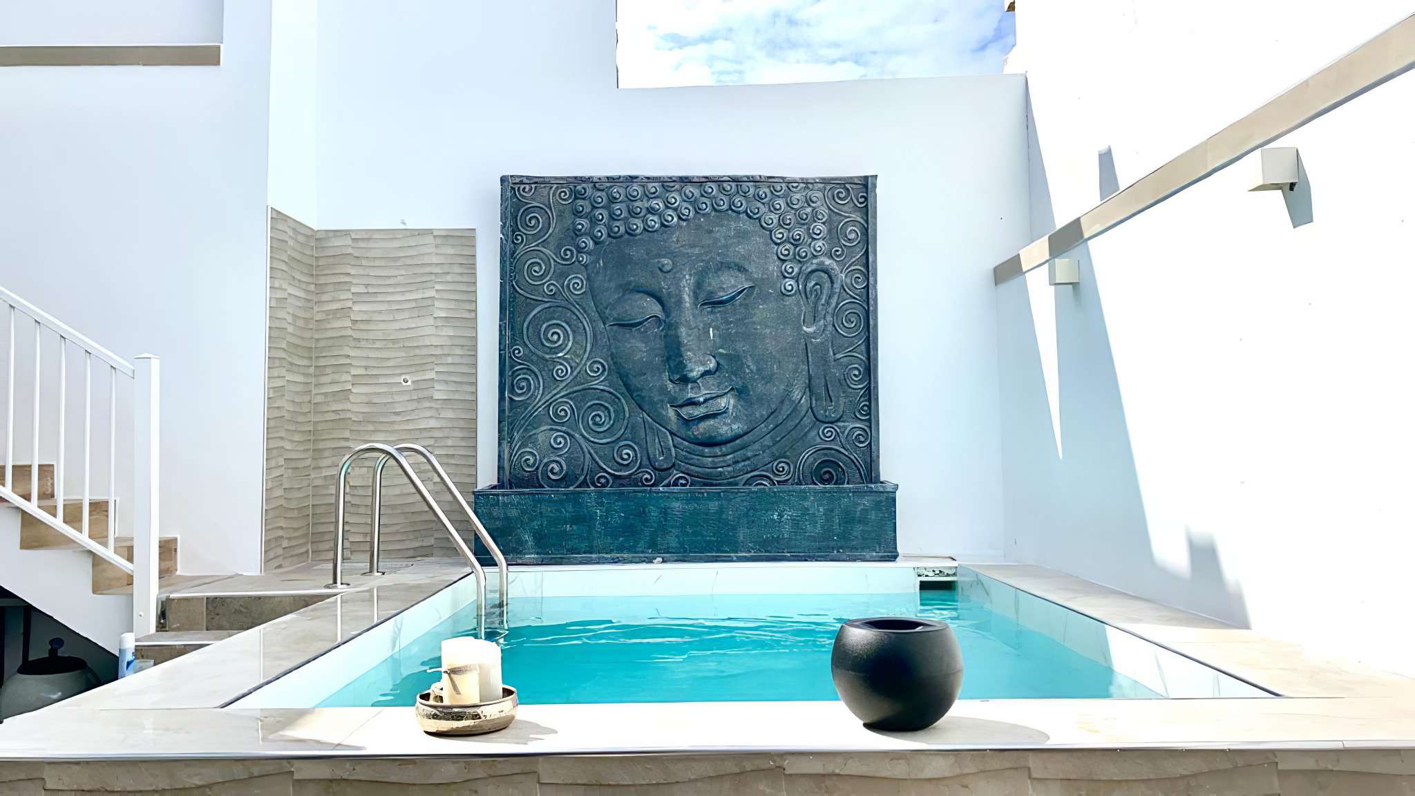 Piscina privada de Villa Dolce Vita con agua turquesa y un gran relieve de Buda